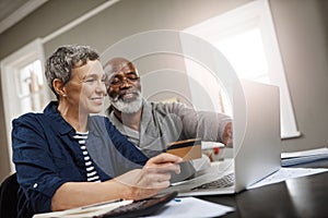 Time to book that retirement vacation. a senior couple using a credit and laptop while working on their finances at home