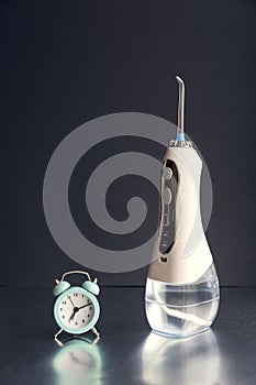 Time to brush your teeth. Oral irrigator and an alarm clock. on a black