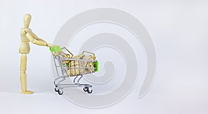 Time to buy a car. Miniature shopping cart with wooden cars isolated on white. Wooden model of a human. Close-up shot, side view.