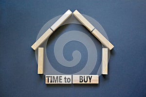 Time to buy house symbol. Concept words `Time to buy` on wooden blocks near miniature house. Beautiful grey background, copy spa