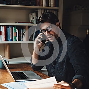 Time to call in few favors. a handsome young businessman making a phone call while working in his office at home.