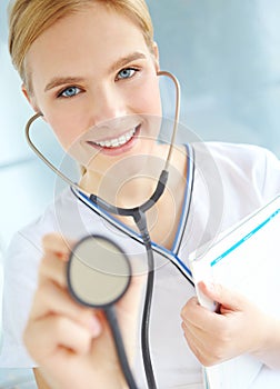 Time to check that heartbeat. Portrait of a pretty nurse holding up a stethoscope while holding a medical file.