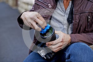 Time to clean this lens. A young man removing the lens from his camera.