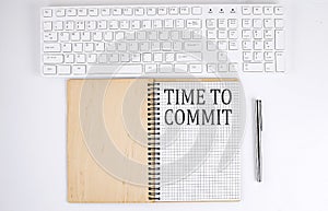 TIME TO COMMIT text on the notebook with keyboard on white background