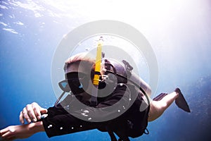 Time to descend. Young female scuba diver floating through the water as she checks her dive computer - Copyspace.