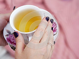 A cup of tea in the hands of a woman.