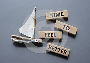 Time to feel better symbol. Wooden blocks with words Time to feel better. Beautiful grey background with boat. Medicine and Time