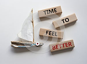 Time to feel better symbol. Wooden blocks with words Time to feel better. Beautiful white background with boat. Medicine and Time