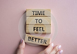 Time to feel better symbol. Wooden blocks with words Time to feel better. Businessman hand. Beautiful pink background. Medicine