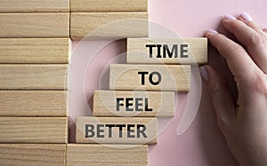 Time to feel better symbol. Wooden blocks with words Time to feel better. Businessman hand. Beautiful pink background. Medicine