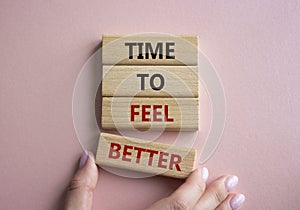 Time to feel better symbol. Wooden blocks with words Time to feel better. Businessman hand. Beautiful pink background. Medicine