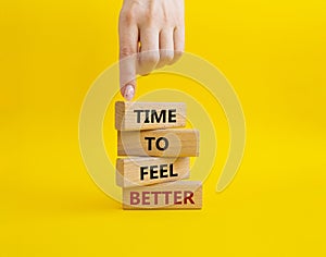 Time to feel better symbol. Wooden blocks with words Time to feel better. Businessman hand. Beautiful yellow background. Medicine