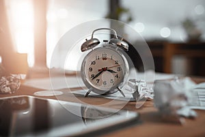 Time to get through those looming deadlines. Still life shot of a clock and crumpled paper on a desk in an office at