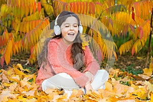 It is time to get in the mood with some great music. Kid girl relaxing near autumn tree with headphones. Music for