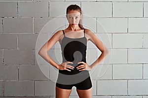 Time to get my fitness on. Cropped portrait of a sporty young woman standing with her hands on her hips against a wall.