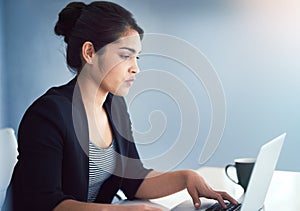 Time to get serious. an attractive young businesswoman working on a laptop in her office.