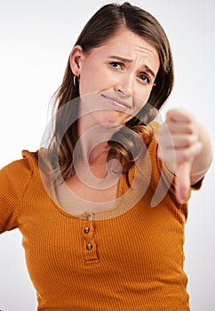 Time to get up for work. Studio shot of a young woman showing thumbs down against a white background.