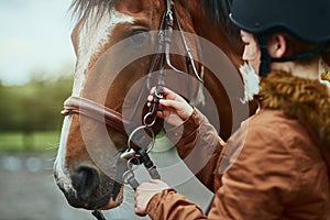 Time to giddy up. a teenage girl preparing to ride her pony on a farm.