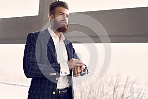 Time to go. Handsome stylish man in blue suit in a cage at home standing near window and checking time