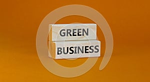 Time to green business symbol. Wooden blocks with words `Green business`. Beautiful orange background. Green success business