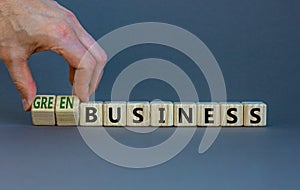 Time to green business symbol. Wooden cubes with words `Green business`. Businessman hand. Beautiful grey background. Green