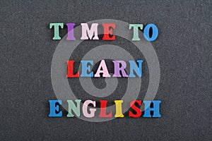 TIME TO LEARN ENGLISH word on black board background composed from colorful abc alphabet block wooden letters, copy