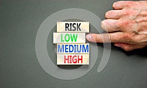 Time to low risk symbol. Concept word Risk low medium high on wooden block. Businessman hand. Beautiful grey table grey background