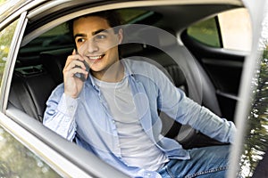 Time to make decision. Confident young businessman working on his laptop and talking on the phone while sitting in the car