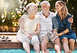 Time to make some summer memories. a happy young woman spending quality time with her elderly parents at the pool.