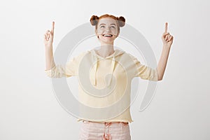 Time to move on next level. Portrait of gorgeous happy young woman with ginger hair looking and pointing up with raised