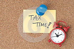 Time to planning for tax or reminder for tax payment concept, Thumbtack pushpin with alarm clock on small paper note written the