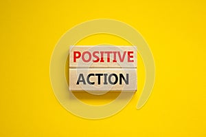 Time to positive action symbol. Wooden blocks with concept words `Positive action`. Beautiful yellow background. Business and