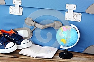 Time to prepare for holiday with retro suitcase, passport, sneakers and globe on wooden table â€“ travel concept