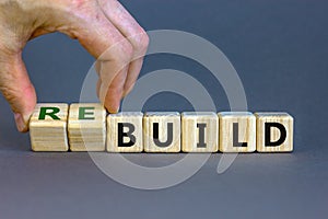 Time to rebuild. Concept words `build` and `rebuild` on cubes on a beautiful grey background. Male hand.  Business concept. Co