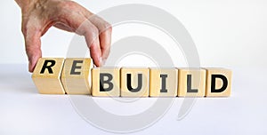 Time to rebuild symbol. Businessman turns wooden cubes and changes the word `build` to `rebuild`. Beautiful white background.