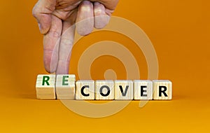 Time to recover symbol. Businessman turns wooden cubes and changes the word `cover` to `recover`. Beautiful orange table, oran