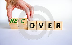 Time to recover symbol. Businessman turns wooden cubes and changes the word `over` to `recover`. Beautiful white table, white