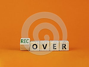 Time to recover symbol. Turned a wooden cube and changed the word `over` to `recover`. Beautiful orange table, orange backgrou