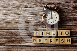 Time To Refresh alphabet letter with alarm clock on wooden background