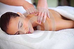 Time to relax. a young woman enjoying a back massage at a spa.