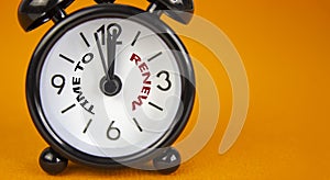 Time to renew symbol. Beautiful black alarm clock with words `time to renew`. Beautiful orange background. Copy space. Business