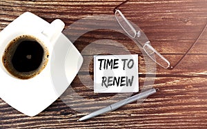 TIME TO RENEW text on sticky with coffee,pen and glasses on the wooden background