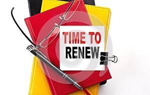 TIME TO RENEW text written on a sticky on colorful notebooks