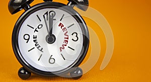 Time to review symbol. Beautiful black alarm clock with words `time to review`. Beautiful orange background. Copy space. Busines
