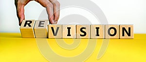 Time to revision. Hand turns cubes and changes the word `vision` to `revision` or vice versa. Beautiful yellow table, white