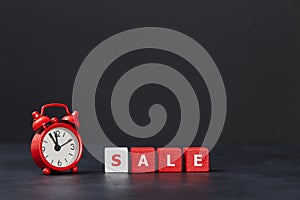 Time to sale. Black friday. Sell-out. Total sale. Red cubes with one white, alarm clock on dark background, copy space