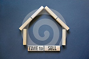 Time to sell house symbol. Concept words `Time to sell` on wooden blocks near miniature house. Beautiful grey background, copy