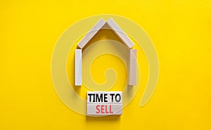 Time to sell house symbol. Concept words `Time to sell` on wooden blocks near miniature house. Beautiful yellow background, copy