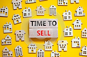 Time to sell house symbol. Concept words `Time to sell` on wooden blocks near miniature houses. Beautiful yellow background, cop