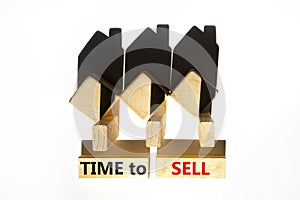 Time to sell house symbol. Concept words `Time to sell` on wooden blocks near miniature houses from shadows. Beautiful white